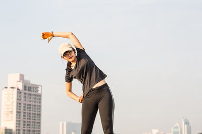 Woman exercising against sky