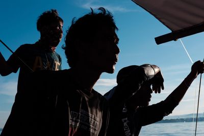 Low angle view of silhouette man photographing against blue sky