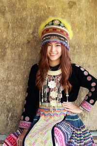 Portrait of smiling woman in traditional clothing against wall