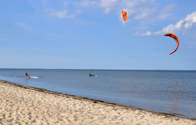 People kiteboarding on sea against sky