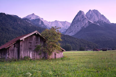 House on field by mountain against sky