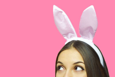 Cropped image of woman wearing bunny headband against pink background