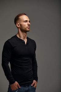 Young man looking away against gray background