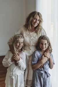 Mother and two daughters standing in narual light studio smiling