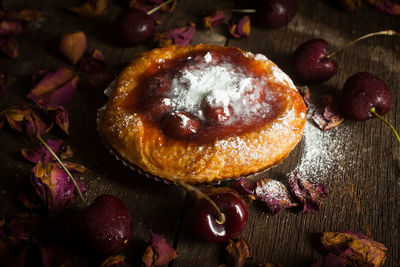 Close-up of sweet pie with cherries and rose petals on table