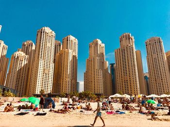 Crowd on beach against buildings in city