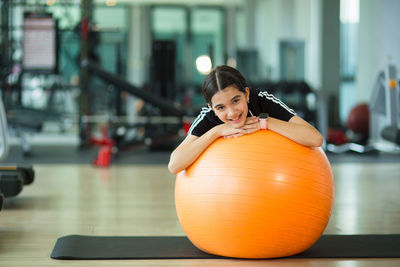 Portrait of smiling girl over fitness ball in gym