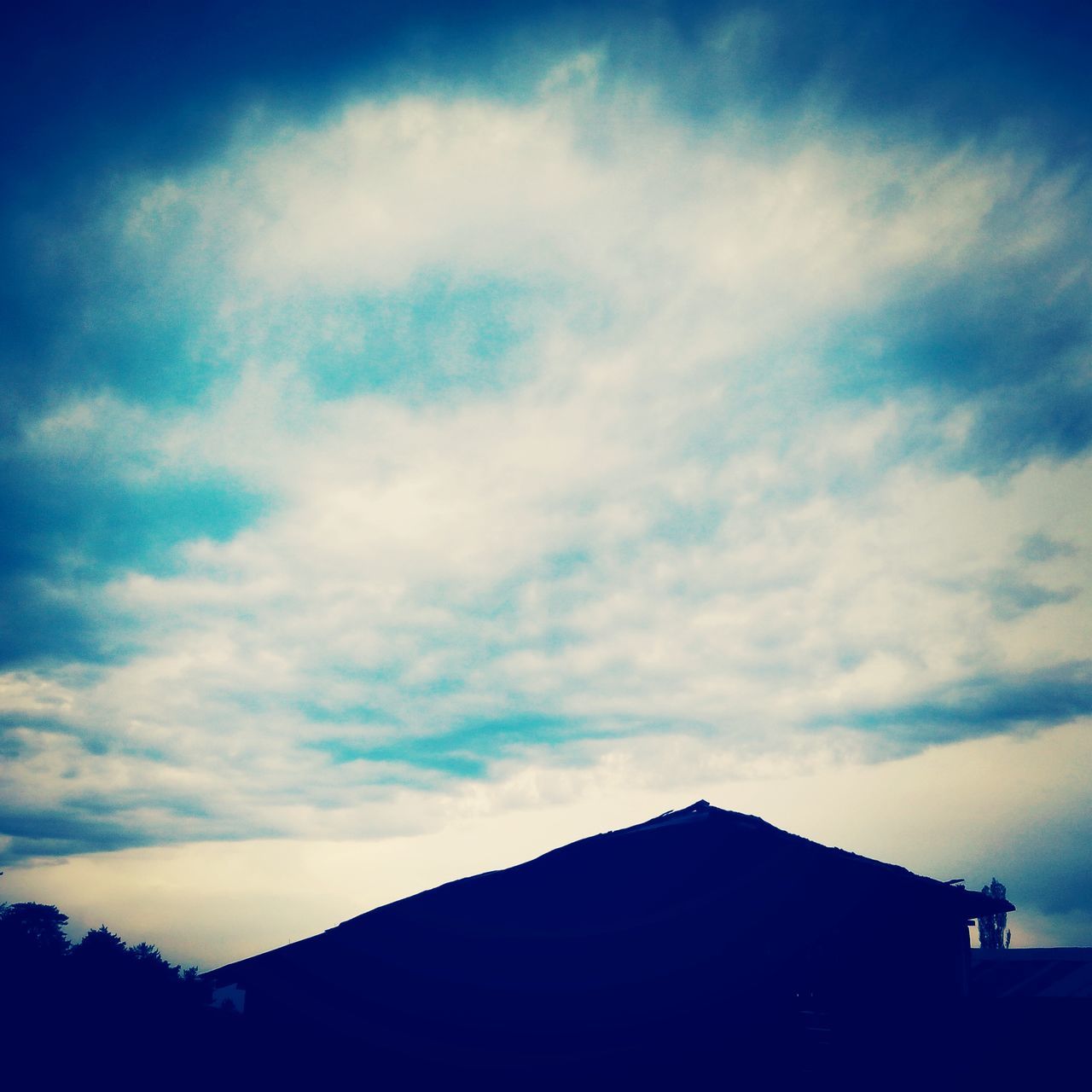 sky, silhouette, building exterior, built structure, cloud - sky, architecture, low angle view, cloud, house, beauty in nature, scenics, mountain, cloudy, nature, blue, tranquil scene, tranquility, dusk, high section, outdoors