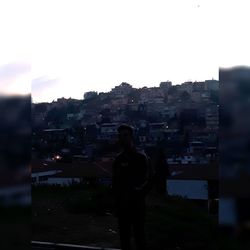 Rear view of silhouette man standing against buildings in city