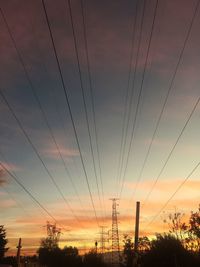 Low angle view of electricity pylon at sunset