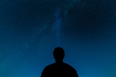 Low angle view of silhouette man standing against star field