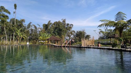 Panoramic view of swimming pool by lake against sky