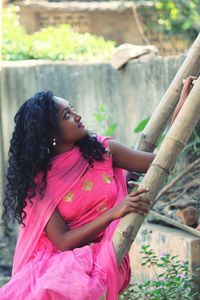 Young woman looking up while sitting on ladder against wall