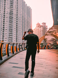 Full length rear view of man photographing in city