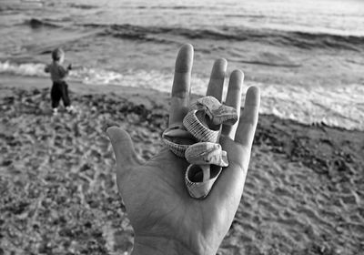 Close-up of hand holding shell on beach