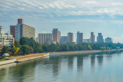 River by buildings in city against sky