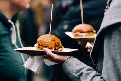 Cropped image of woman holding burgers while standing with friend