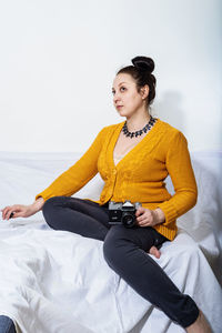 Young woman looking away while sitting on bed