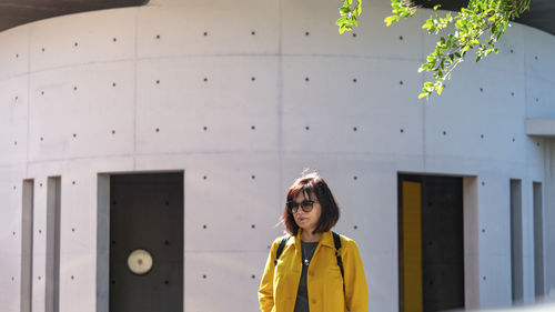 Portrait of woman standing against yellow wall