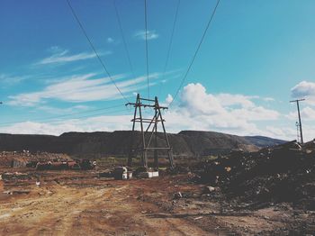 Electricity pylon on land against sky