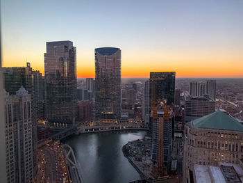River amidst buildings against sky during sunset