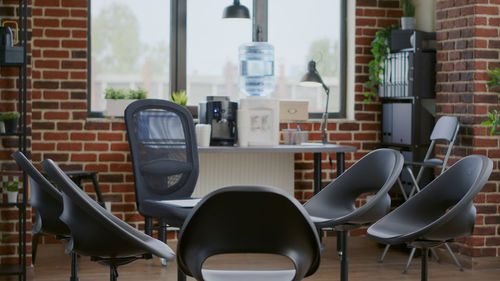 Empty chairs and table against window