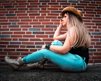 Young woman sitting on brick wall