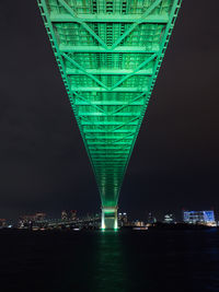 Illuminated bridge over river against sky at night