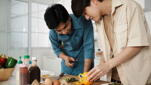 Gay couple cooking sandwich breakfast together in kitchen. happy lgbtq family activity together