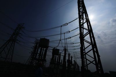 Low angle view of silhouette electricity pylon against sky