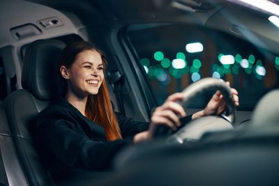 Happy young woman sitting in car