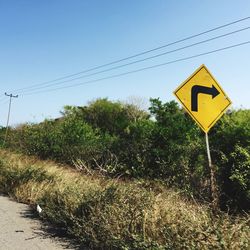 Road sign on landscape against sky