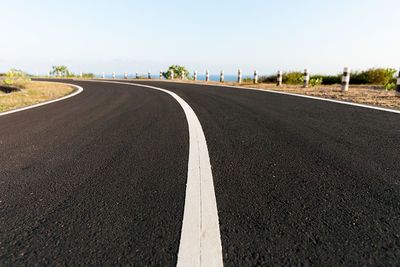 Road amidst grass against clear sky