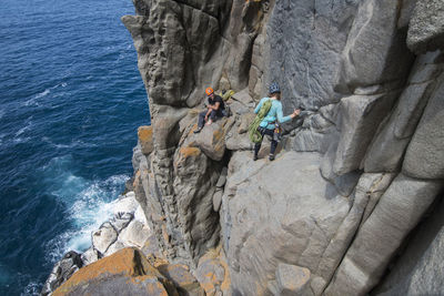 People on rocks by rock formation in water