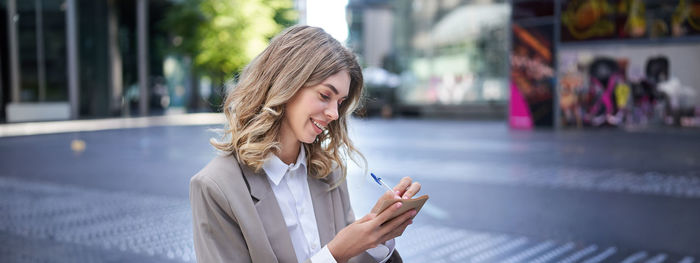 Young woman using mobile phone in city