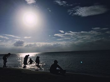 People enjoying at beach against sky