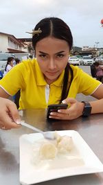 Portrait of young woman holding ice cream in restaurant