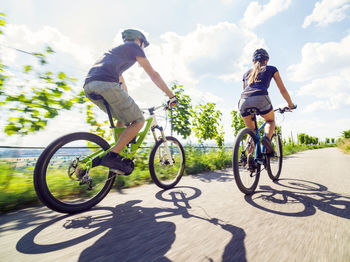 Man riding bicycle on street against sky