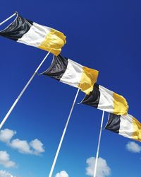 Low angle view of flags waving against blue sky