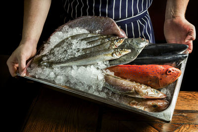 Midsection of man holding fish in tray