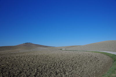 Scenic view of desert against clear blue sky