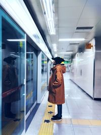 Rear view of woman walking in illuminated bus