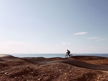 Person riding bike against sky