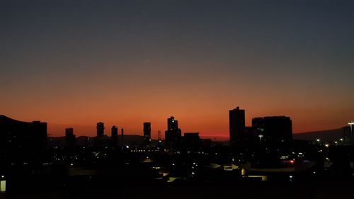 Silhouette buildings in city against sky during sunset