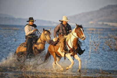 People riding horses in lake