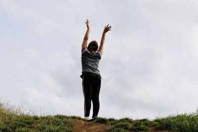 Rear view of woman standing on field against sky