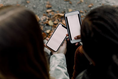 High angle view of teenage girls using social media on smart phones