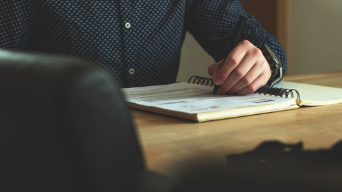 Midsection of woman reading book while sitting on table