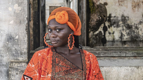 Portrait of woman wearing orange headwear against wall