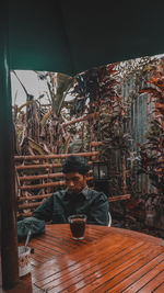 Portrait of young man sitting on table at restaurant